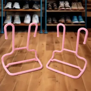 Two pink wire-frame shoe hangers on a wooden floor, shown in front of a shoe rack