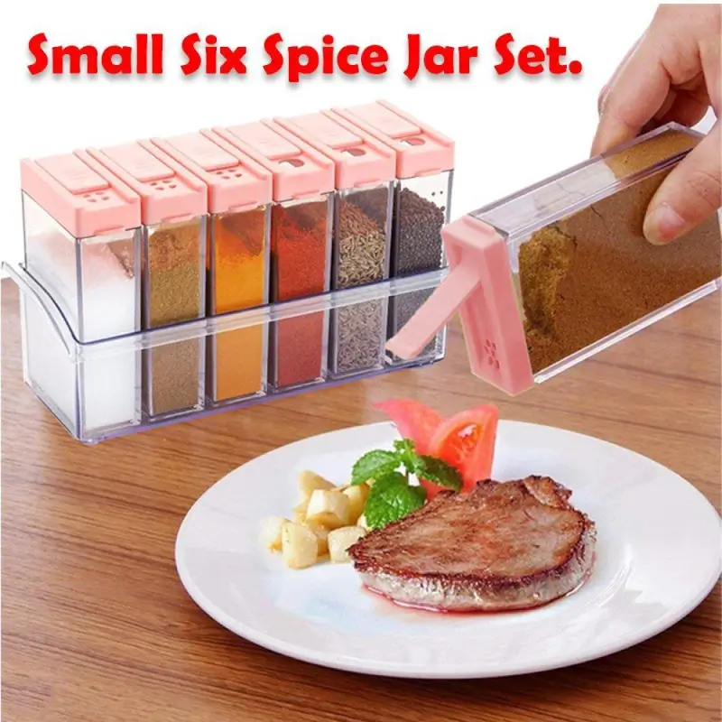 Six spice jars with pink flip-top lids in a clear tray, one jar being used to sprinkle spice onto a plated steak