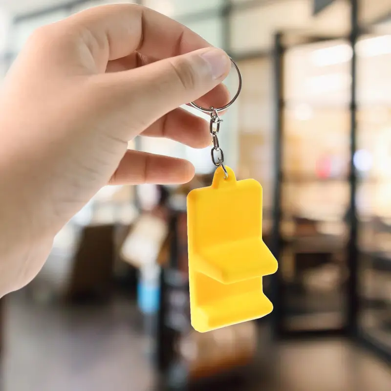 Hand holding the yellow phone stand keychain by its keyring
