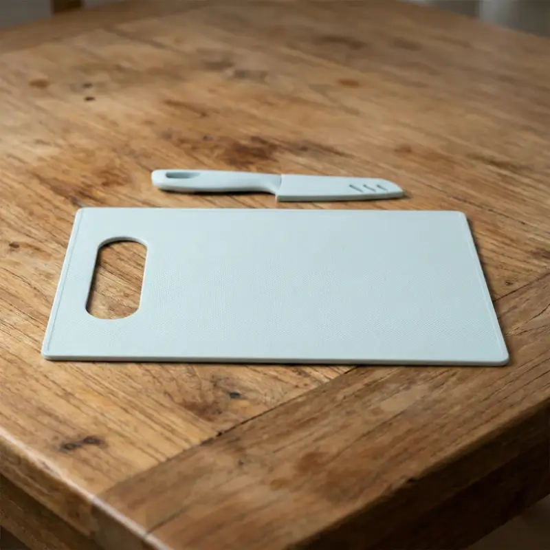 Chopping board, knife and peeler laid on a wooden table