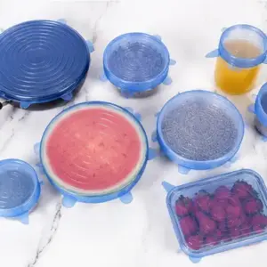 Six blue silicone stretch lids covering a pan, bowls, a cup and a watermelon half on a marble counter