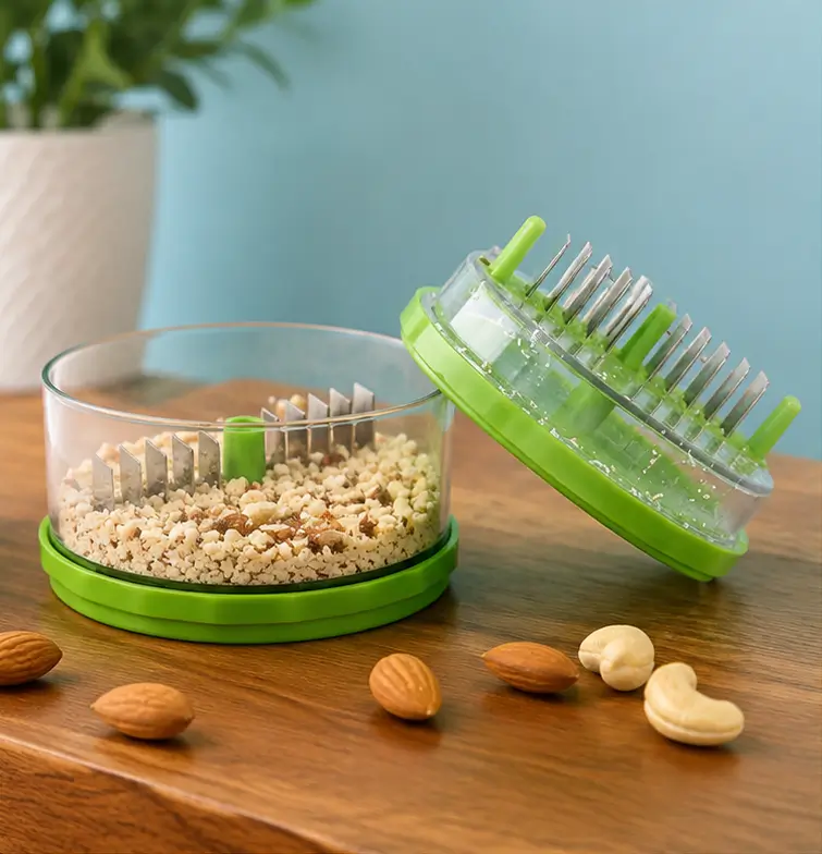 Chopper lid and cup shown open on a wooden table with whole almonds and cashews scattered around